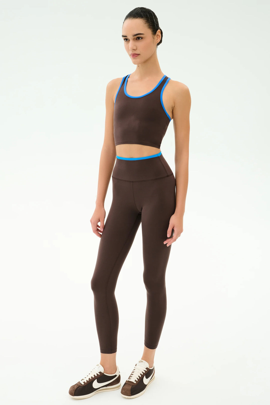Woman wearing a brown sports bra and leggings set on a white background